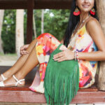 young sexy beautiful woman in colorful dress, summer hippie style, tropical vacation, green handbag with fringe, accessories, hands close up with bracelets, fingers, manicure